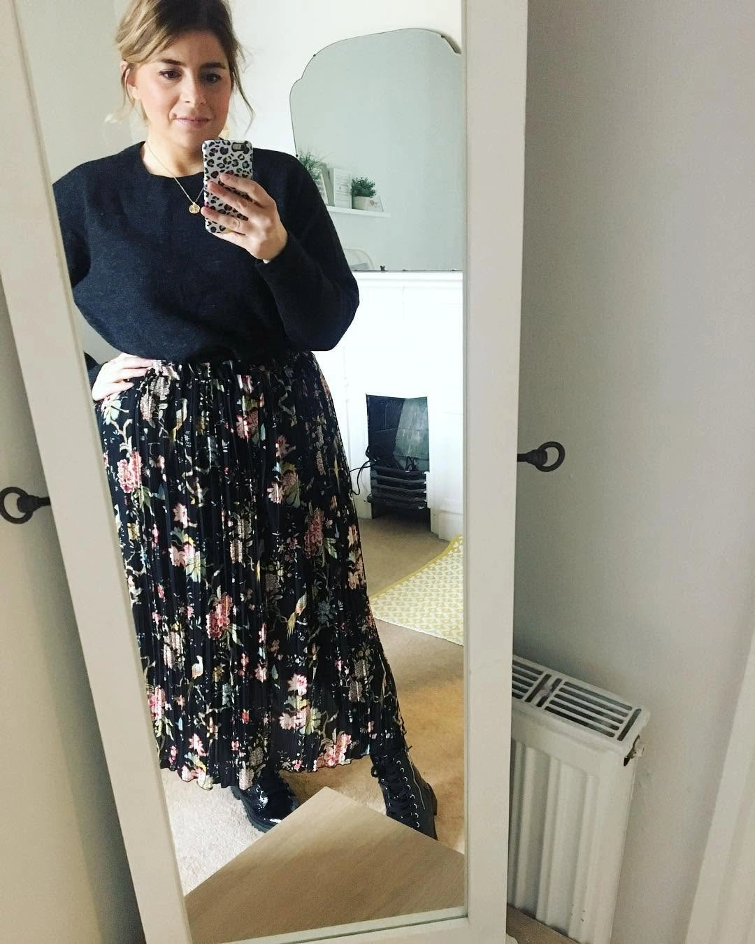Woman in black top, floral pleated skirt, and lace-up boots