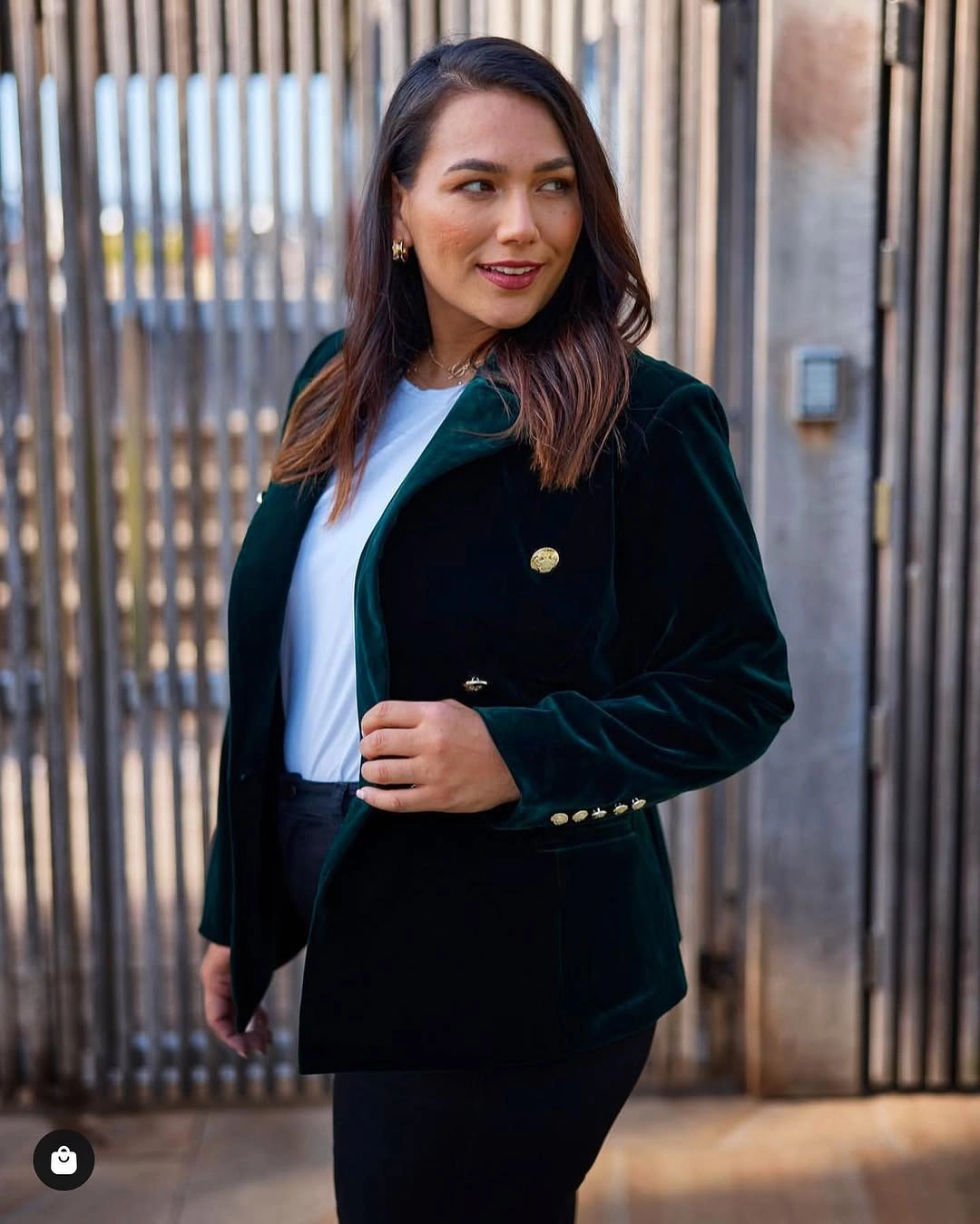 Woman in dark green blazer, white top, and black trousers