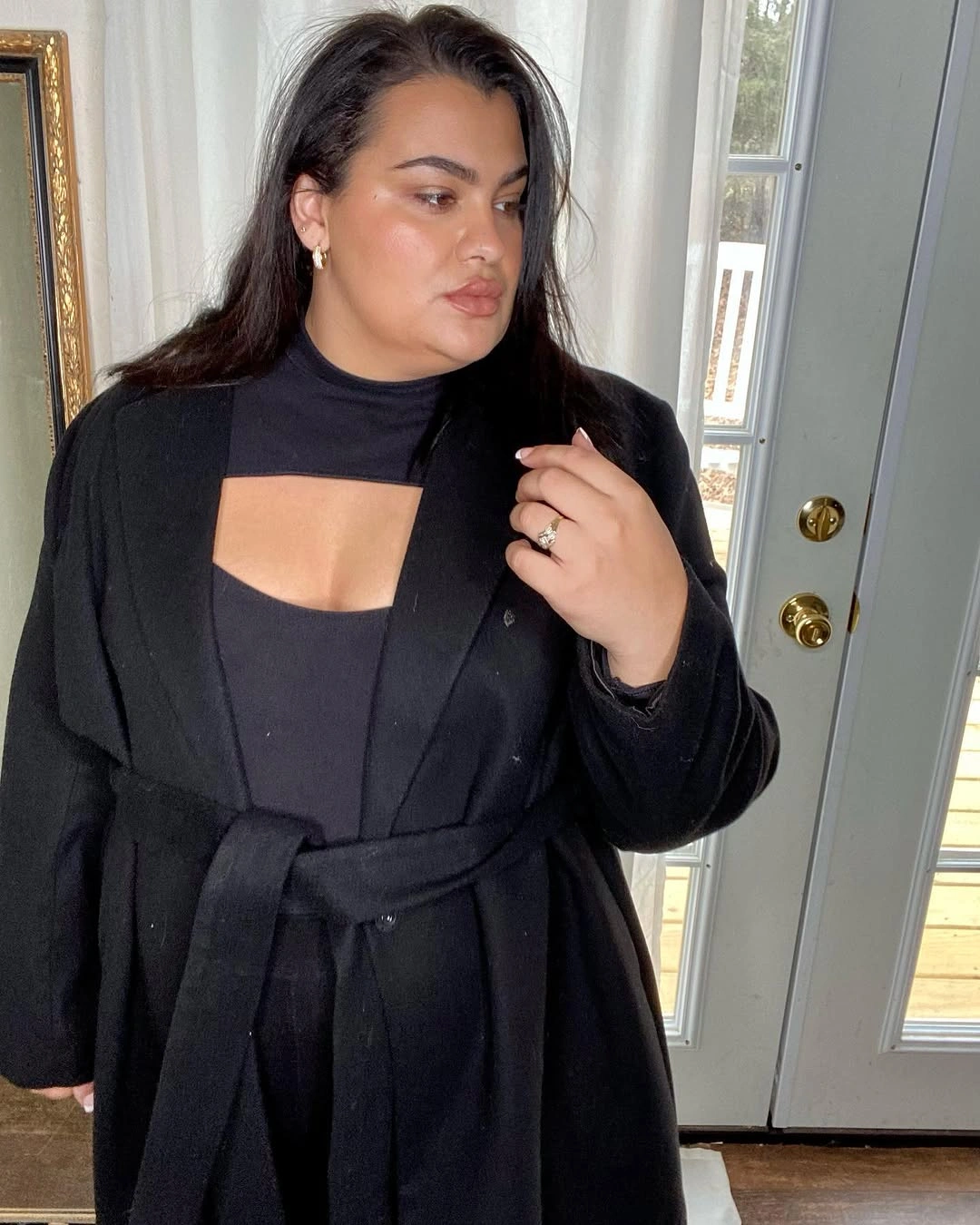Woman in belted black layer and high-neck cutout top