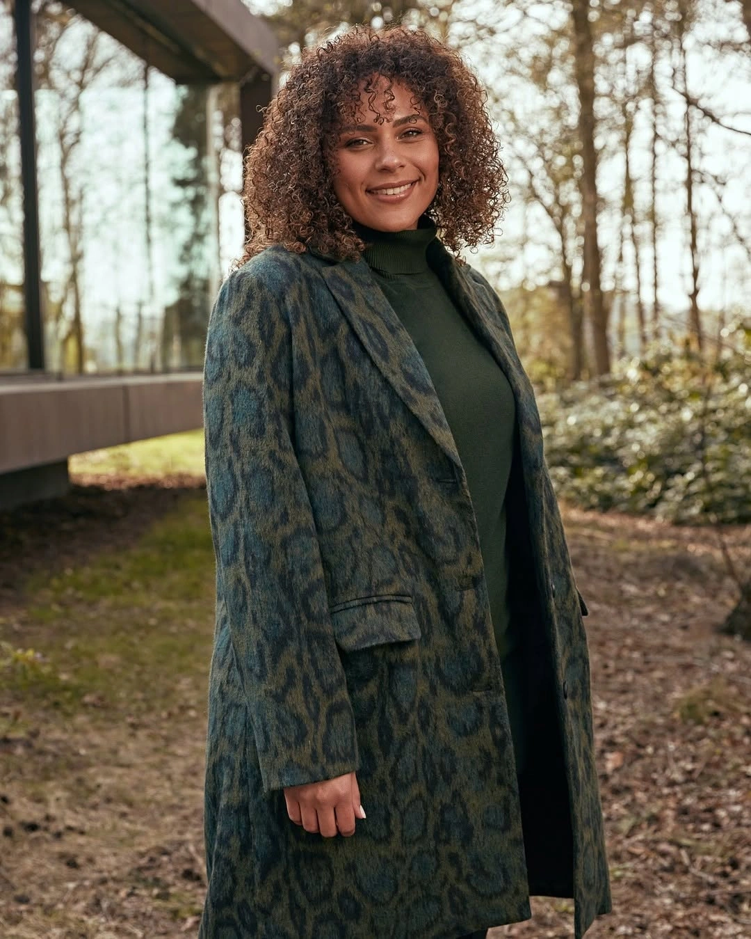 Woman in green patterned coat over dark green turtleneck
