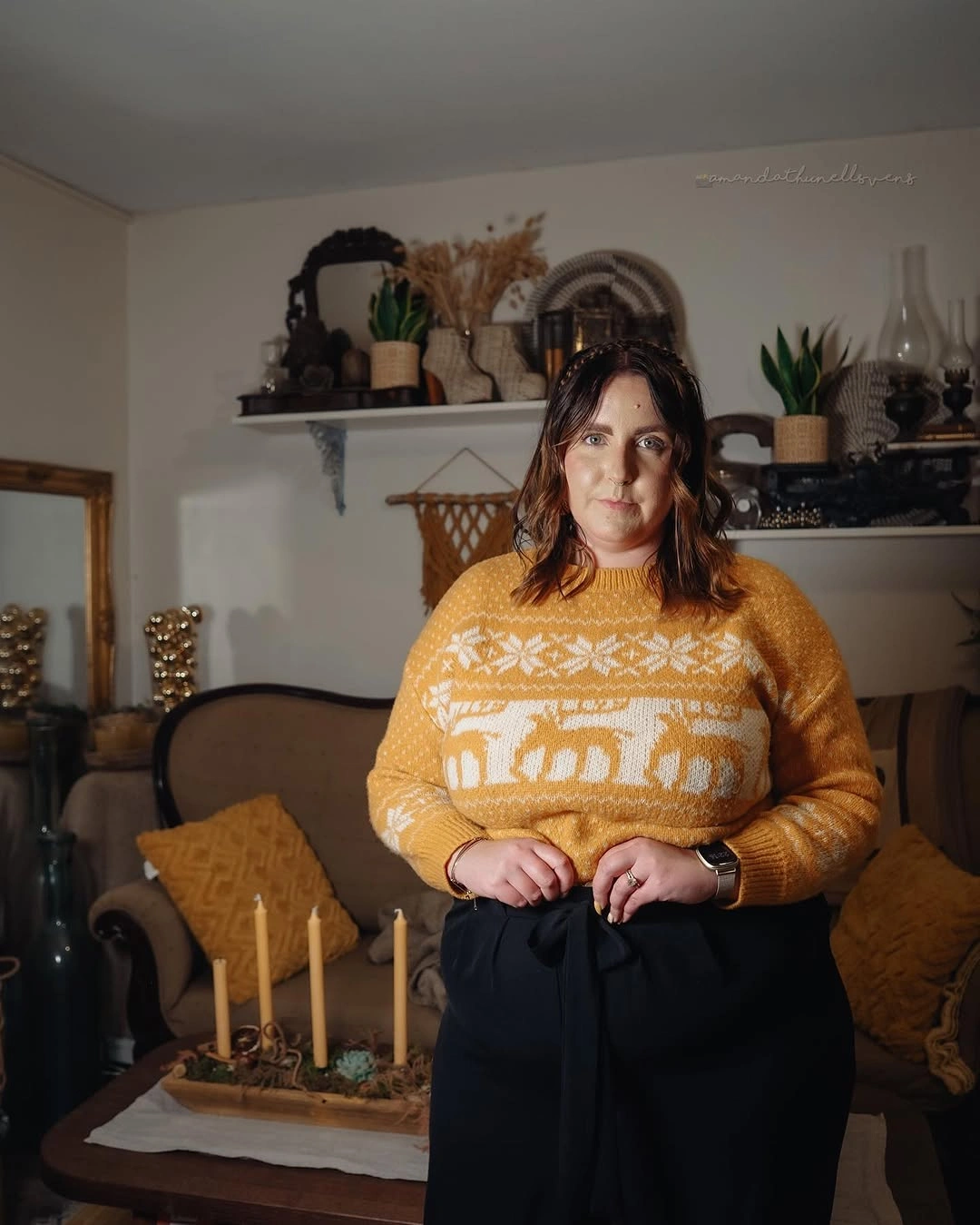Woman in mustard sweater with white motif and black trousers
