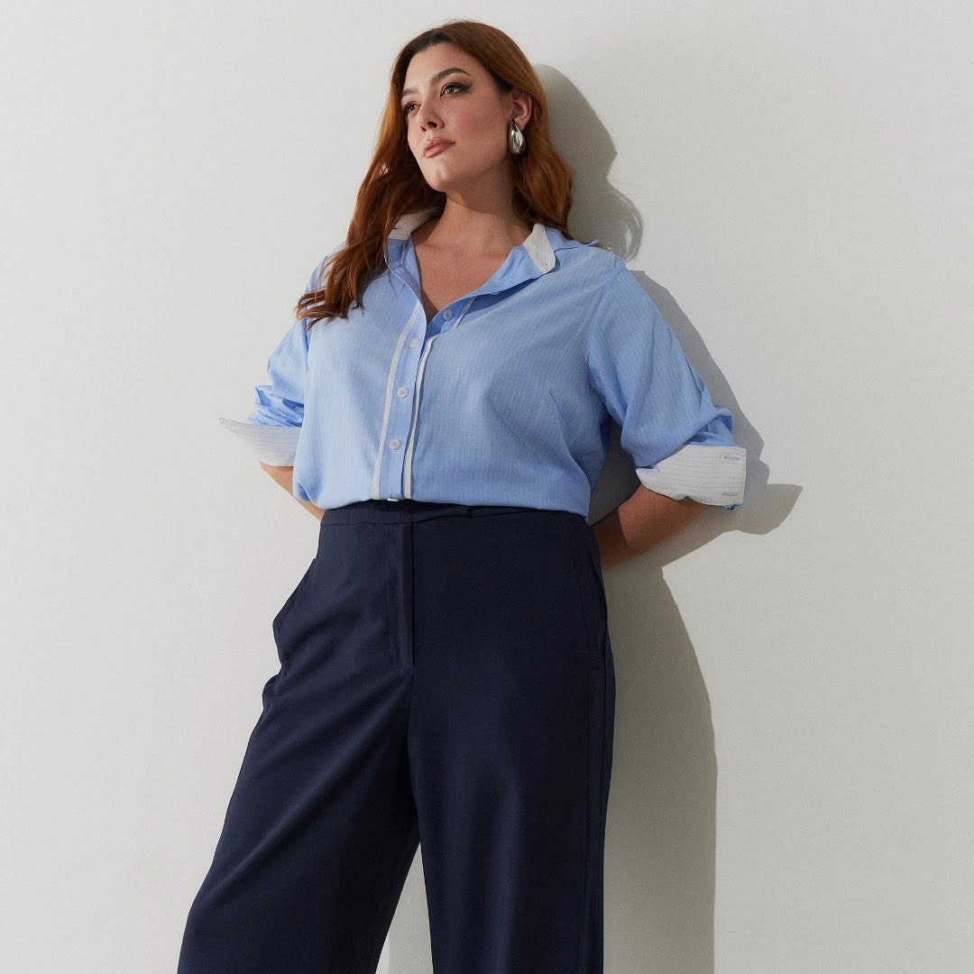 Woman in light blue button-down shirt and navy wide-leg trousers
