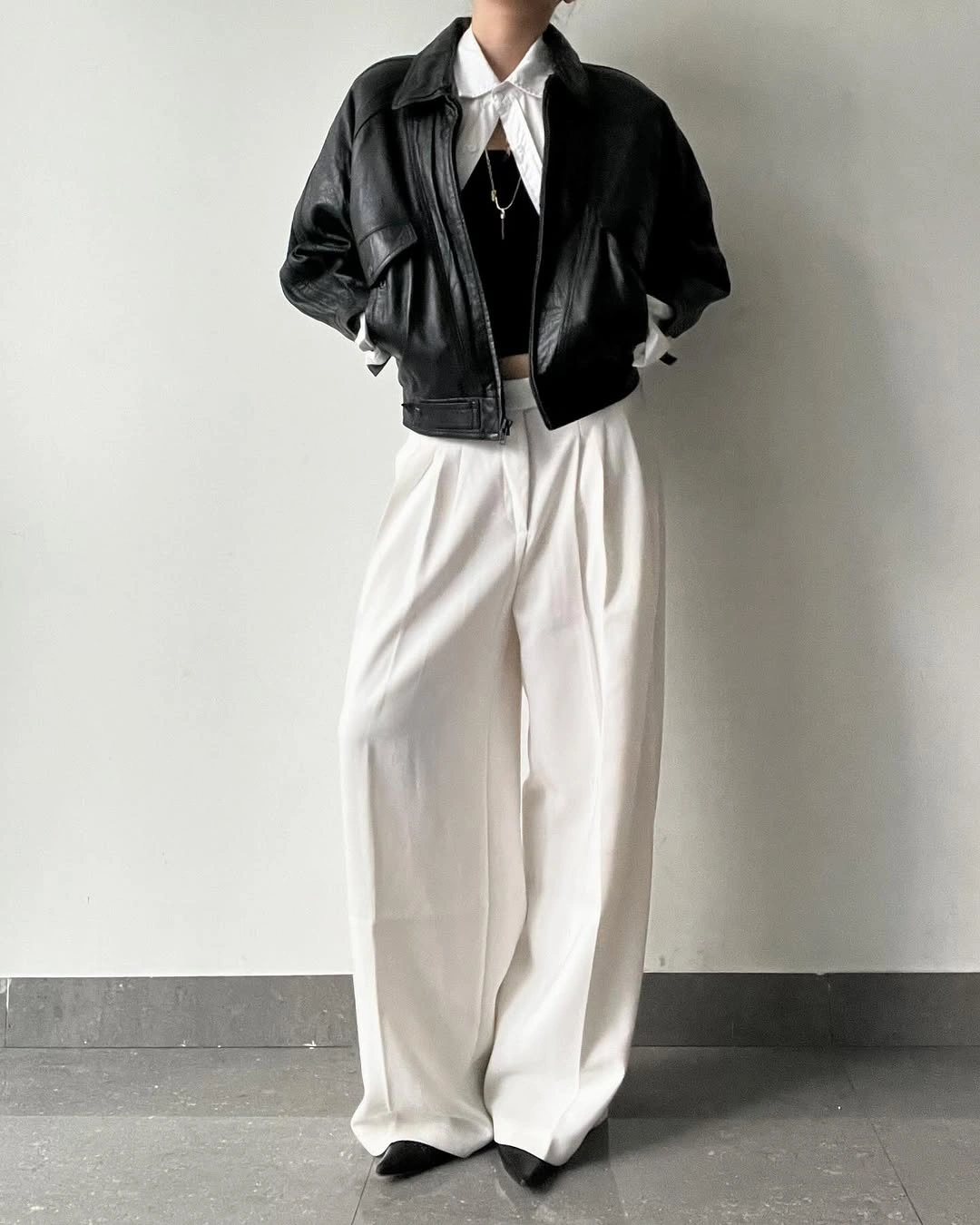 Cropped black jacket, white shirt, wide white trousers, and pointed shoes