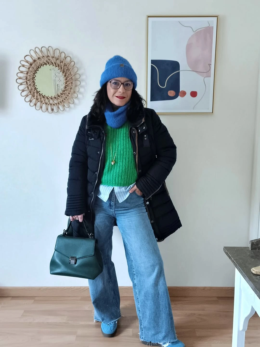 Black quilted coat, green knit, wide jeans, blue beanie, and teal bag