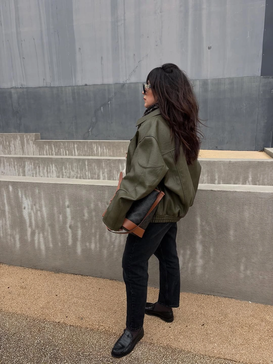 Olive cropped jacket, black trousers, loafers, and rectangular shoulder bag