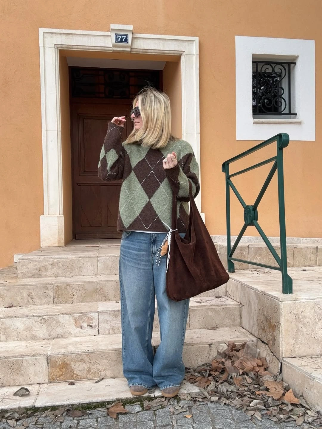 Argyle sweater, wide blue jeans, beige shoes, and dark-brown tote