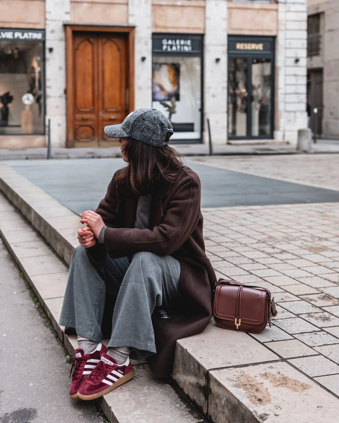 Chocolate brown coat with gray wide trousers burgundy sneakers and bag
