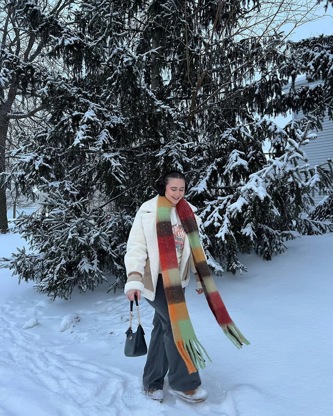 White puffer jacket gray trousers with long multicolor striped scarf