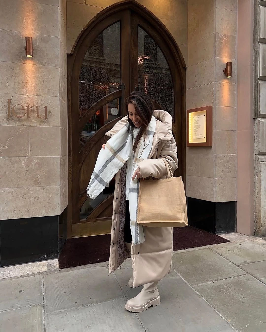 Long beige padded coat with white scarf chunky light boots and tote