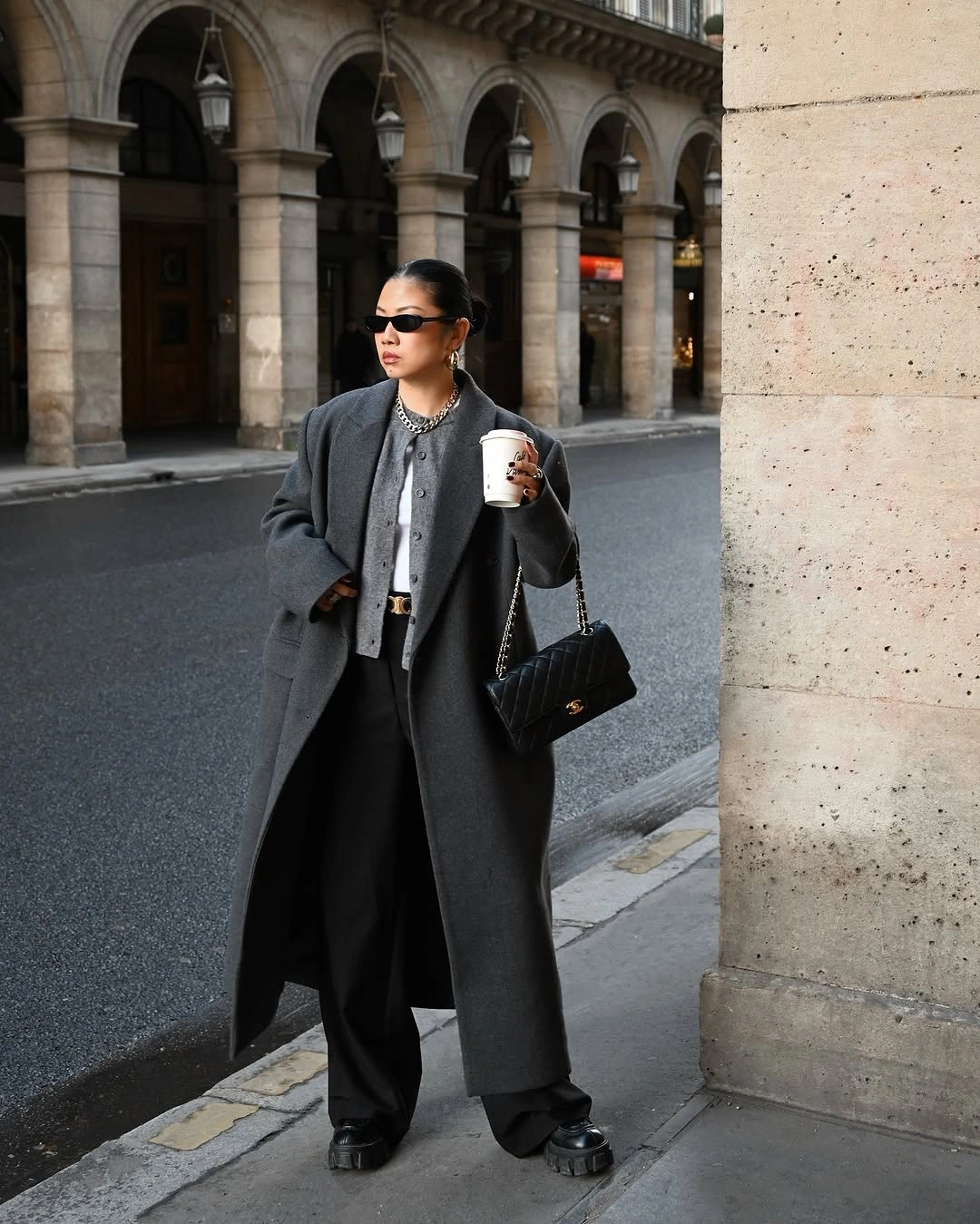 Charcoal long coat with black wide trousers and compact black handbag