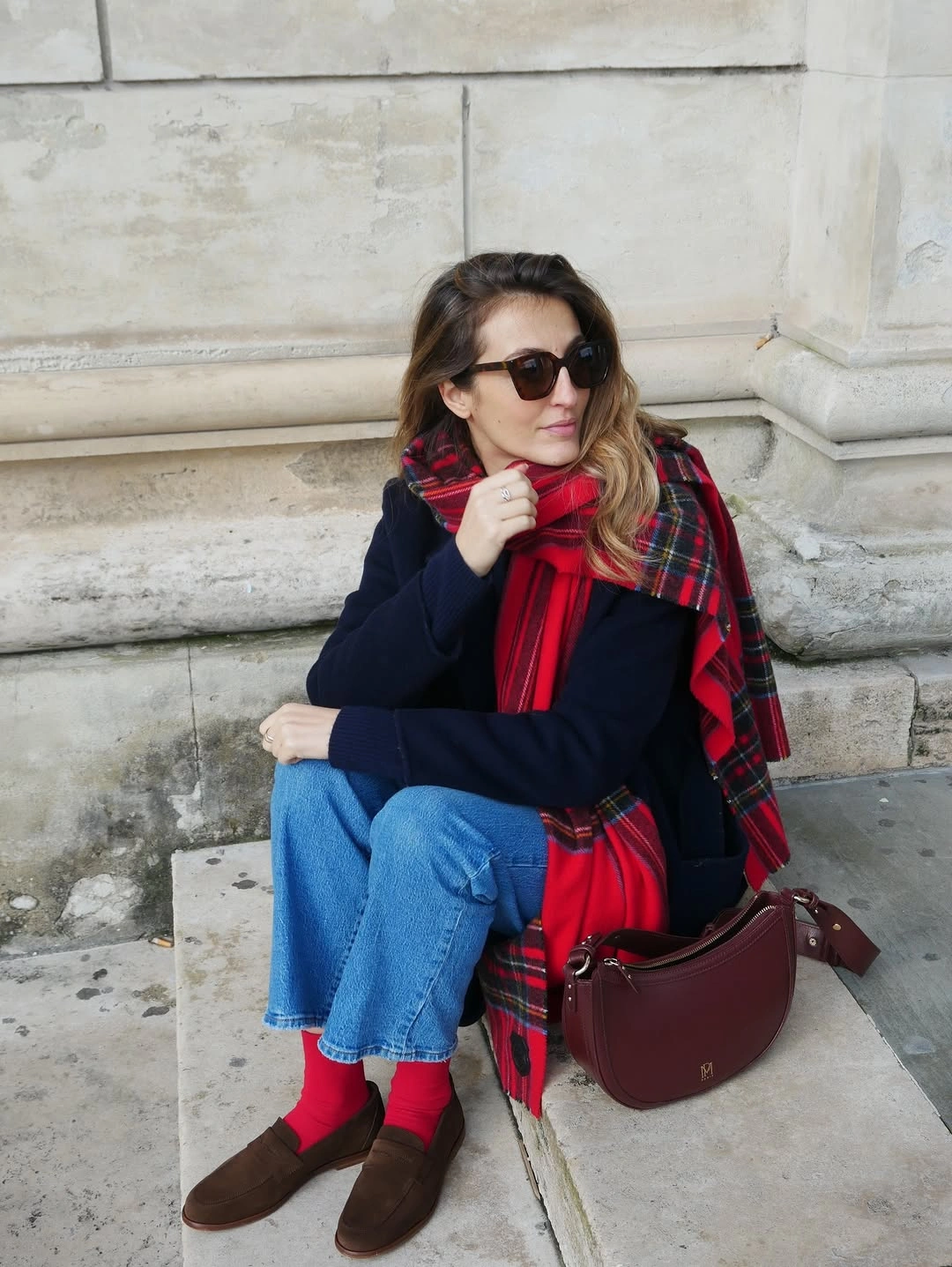 Navy sweater and blue jeans with red tartan scarf and red socks