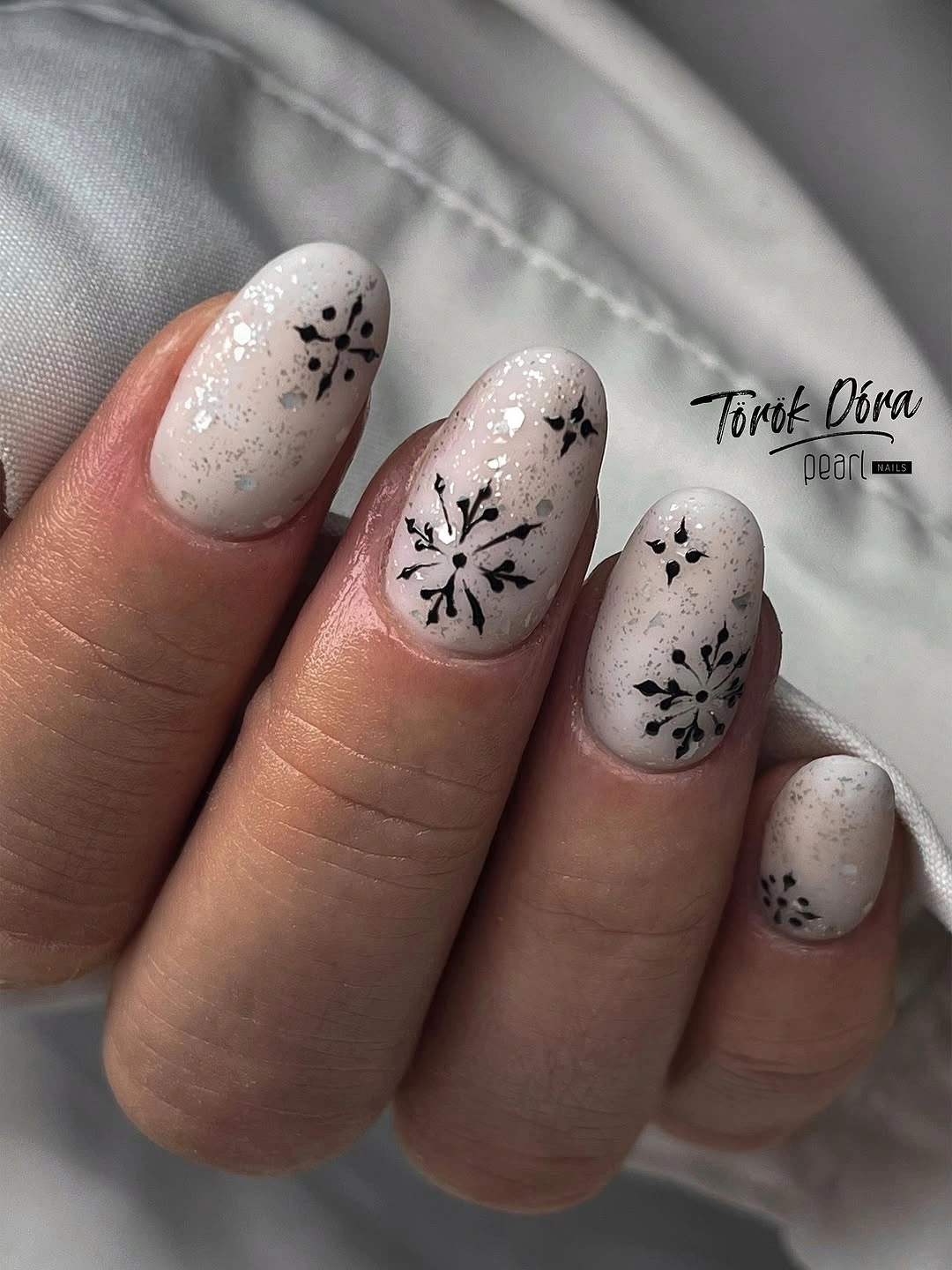 Short white nails with black burst art and speckled texture