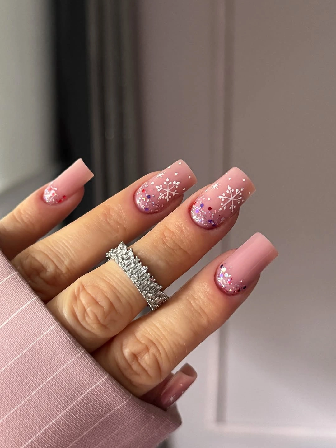 Long pink square nails with glitter gradients and white snowflakes