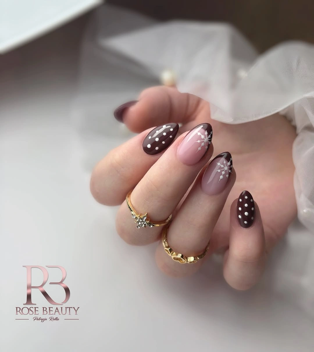 Glossy almond nails with brown polish, dots and snowflake accents