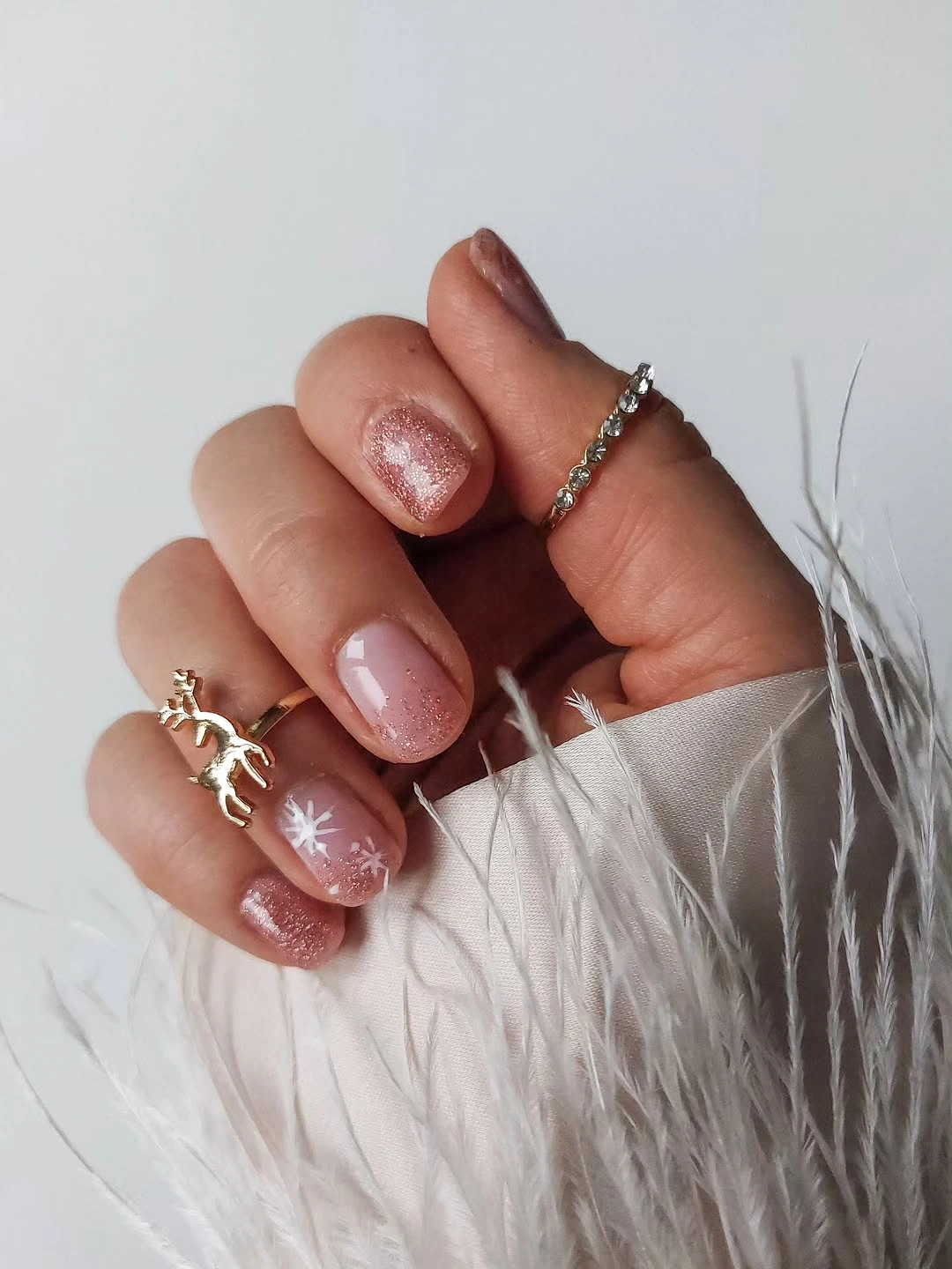 Short blush shimmer nails with white snowflake and rings