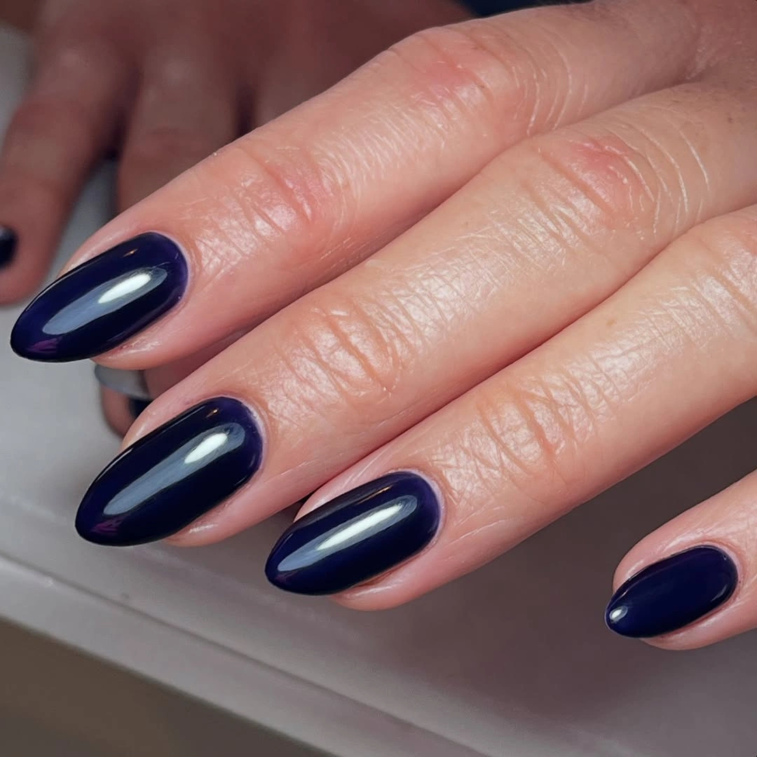 Glossy deep navy oval nails with reflective shine