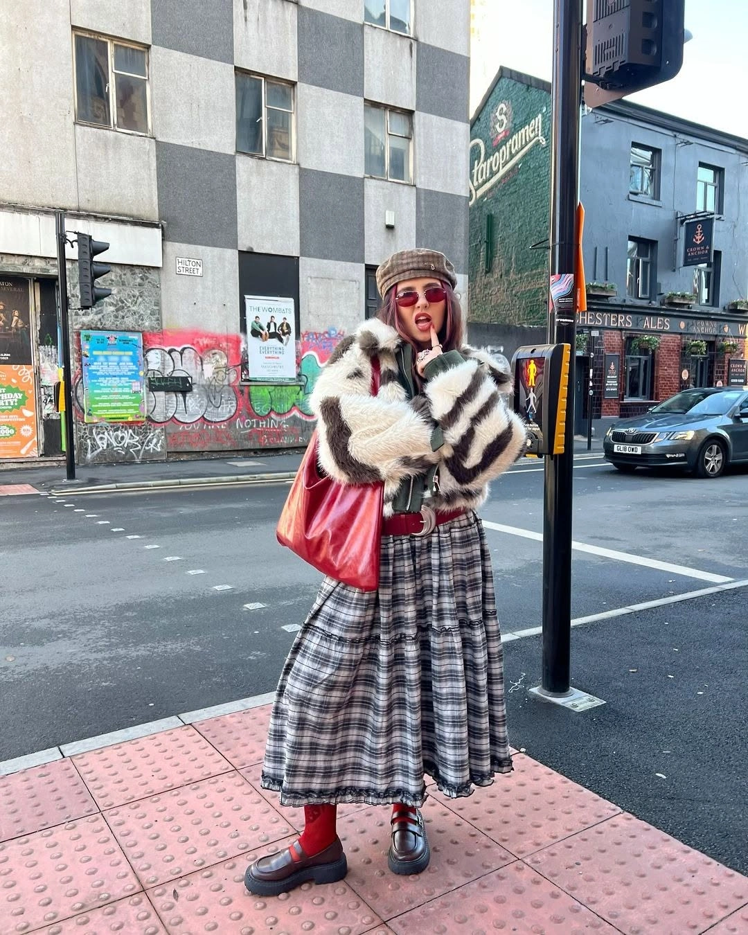 Striped faux-fur-style coat, plaid skirt, red tights and red bag