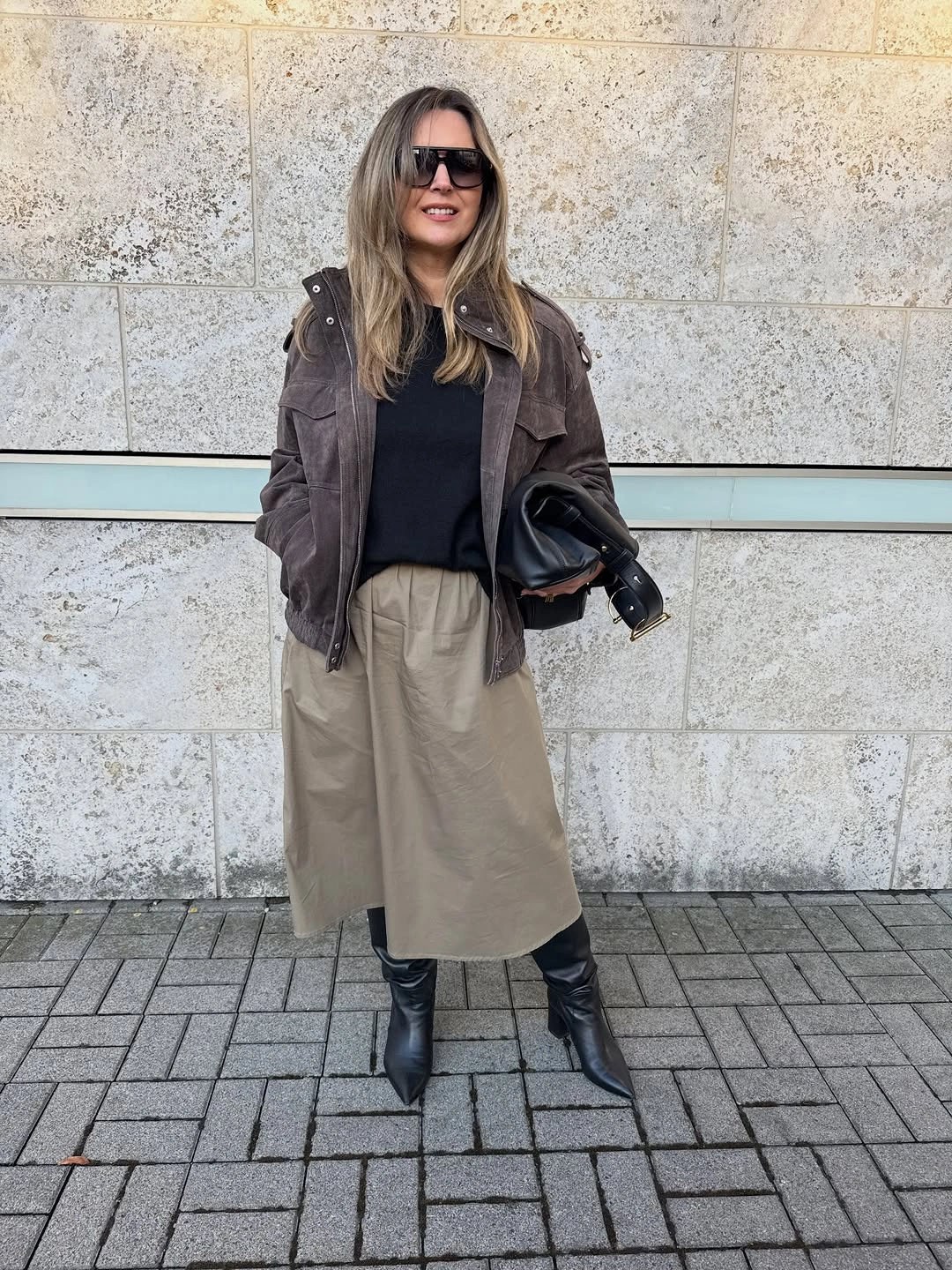 Brown jacket, dark top, beige A-line skirt and black ankle boots
