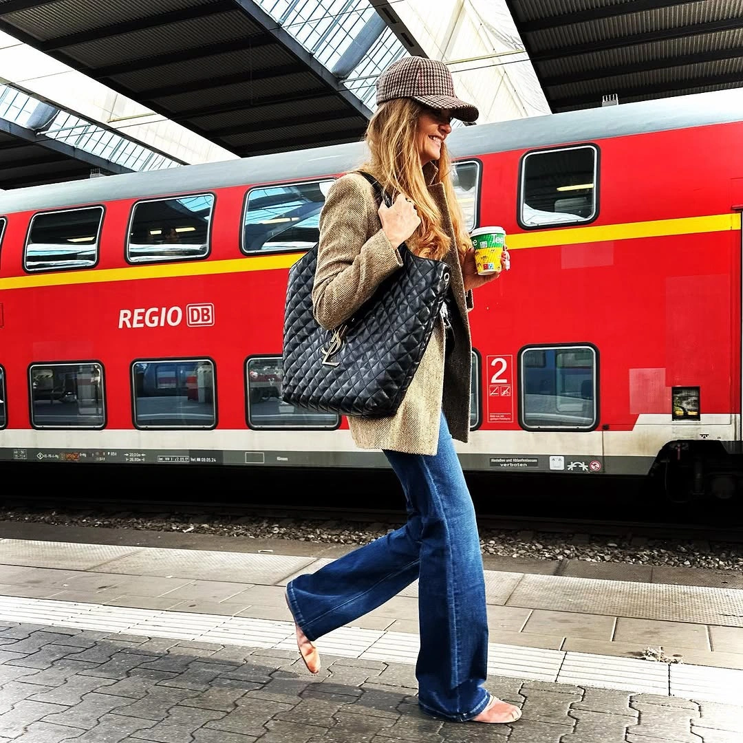 Long neutral jacket with wide jeans and quilted tote on platform