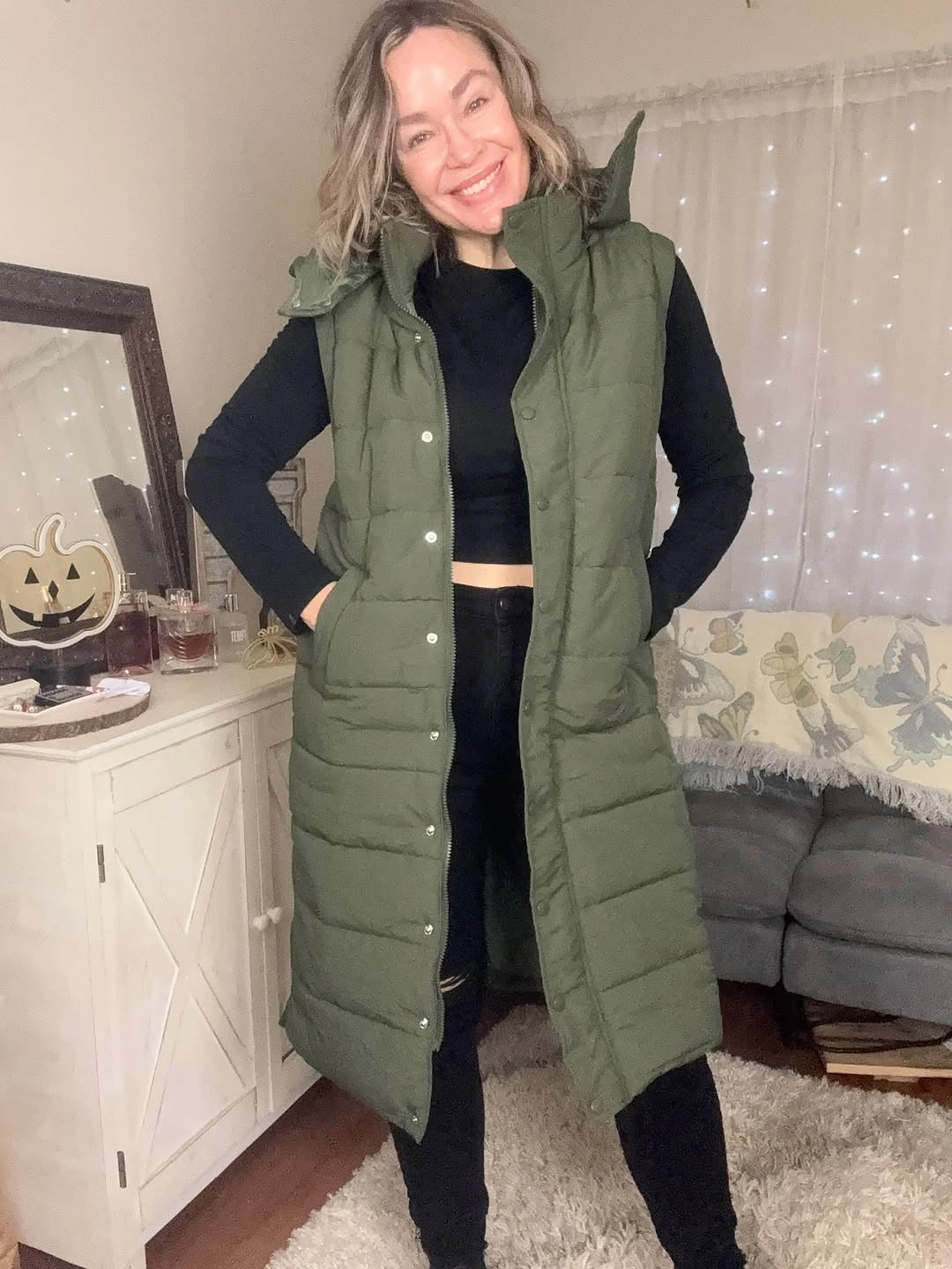 Olive long puffer vest over black top and black bottoms