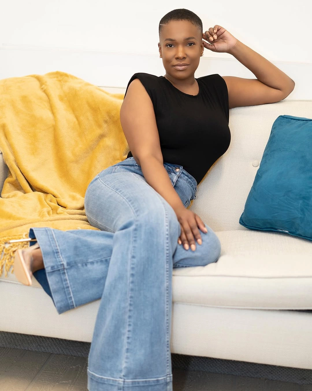 Black sleeveless top with wide light jeans in pale room