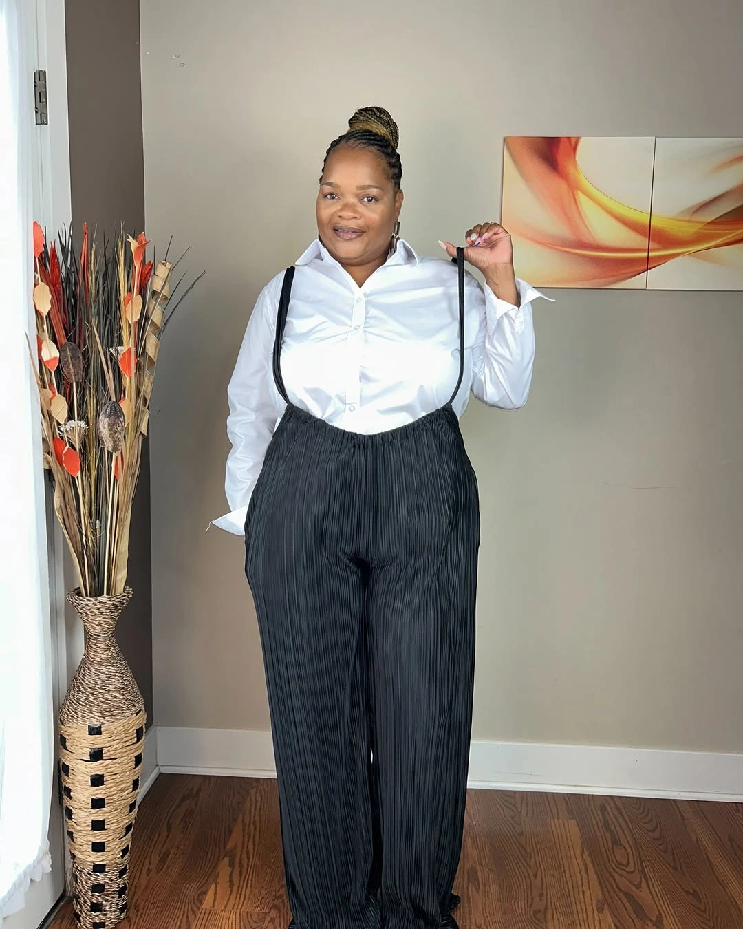 White button-down shirt with dark pleated trousers and straps