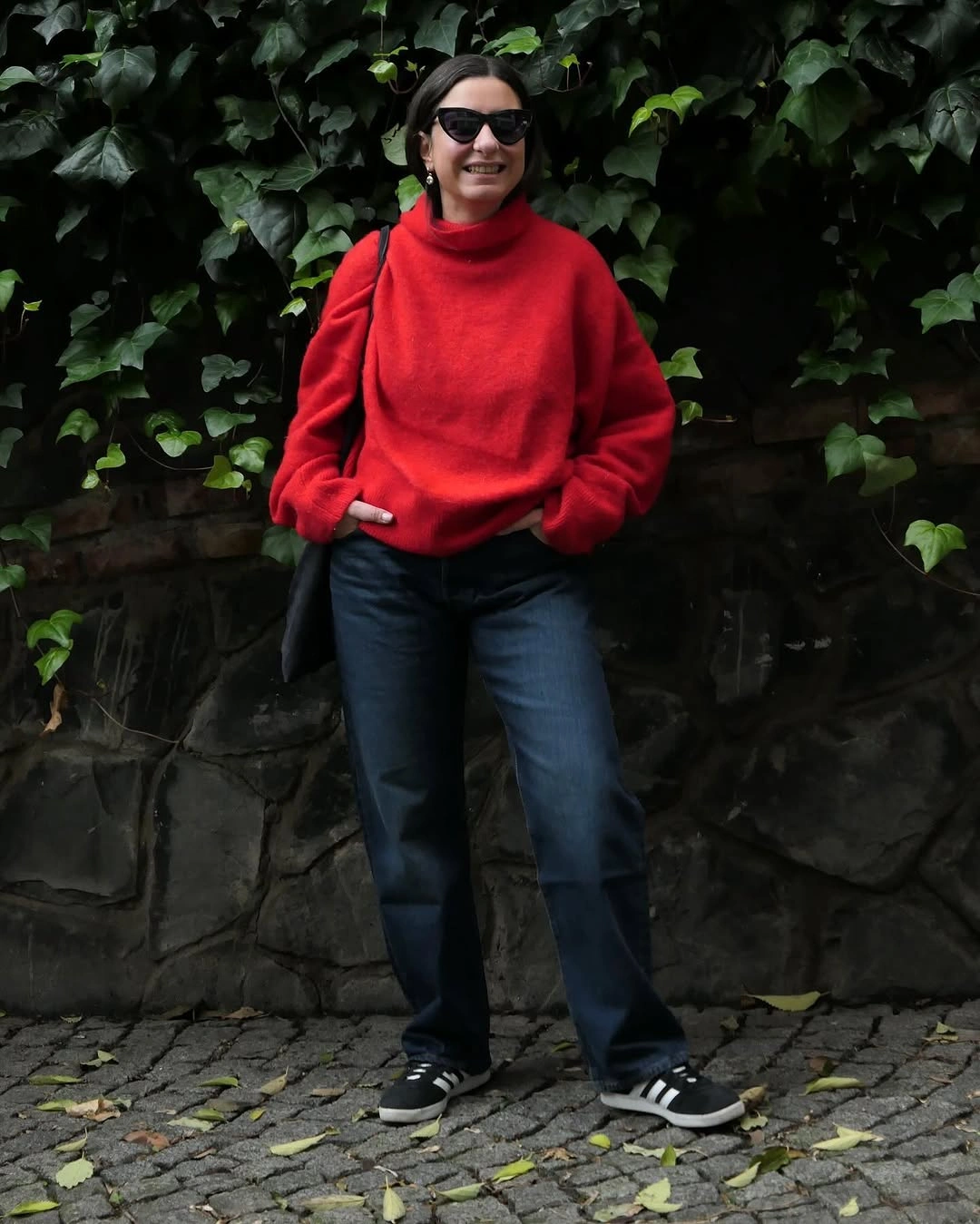 Red oversized turtleneck with dark jeans and black striped sneakers