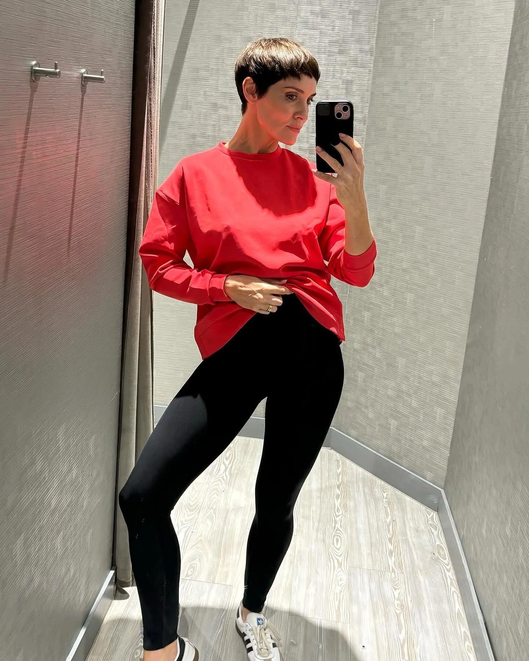 Red oversized sweatshirt with black leggings and white sneakers