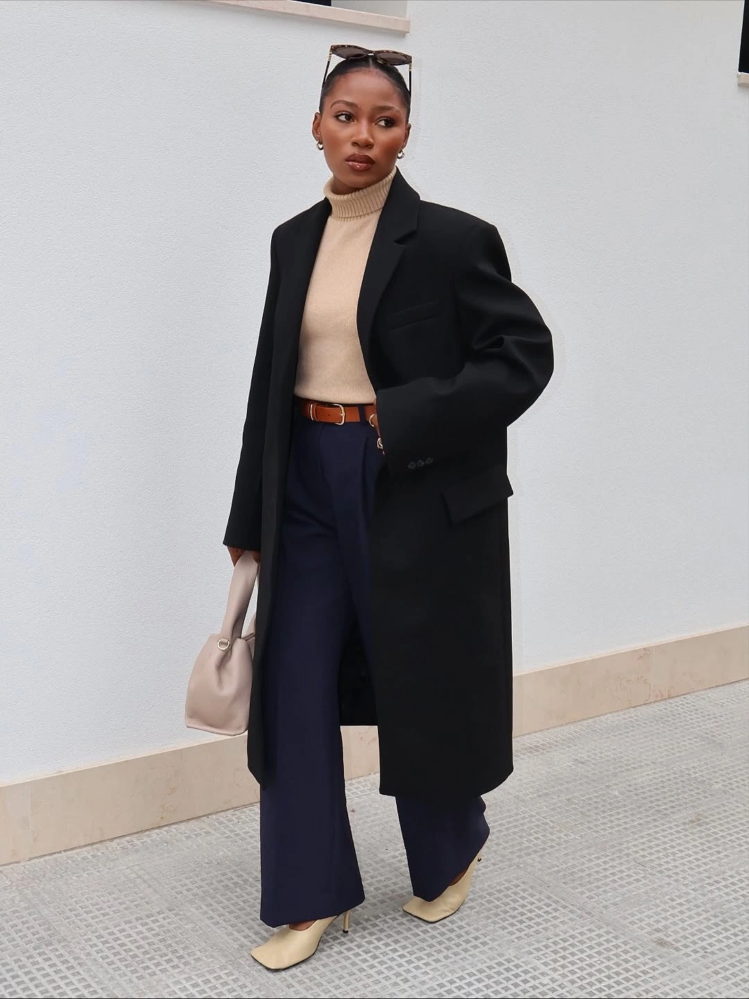 Long black coat with beige turtleneck, navy trousers and cream accessories