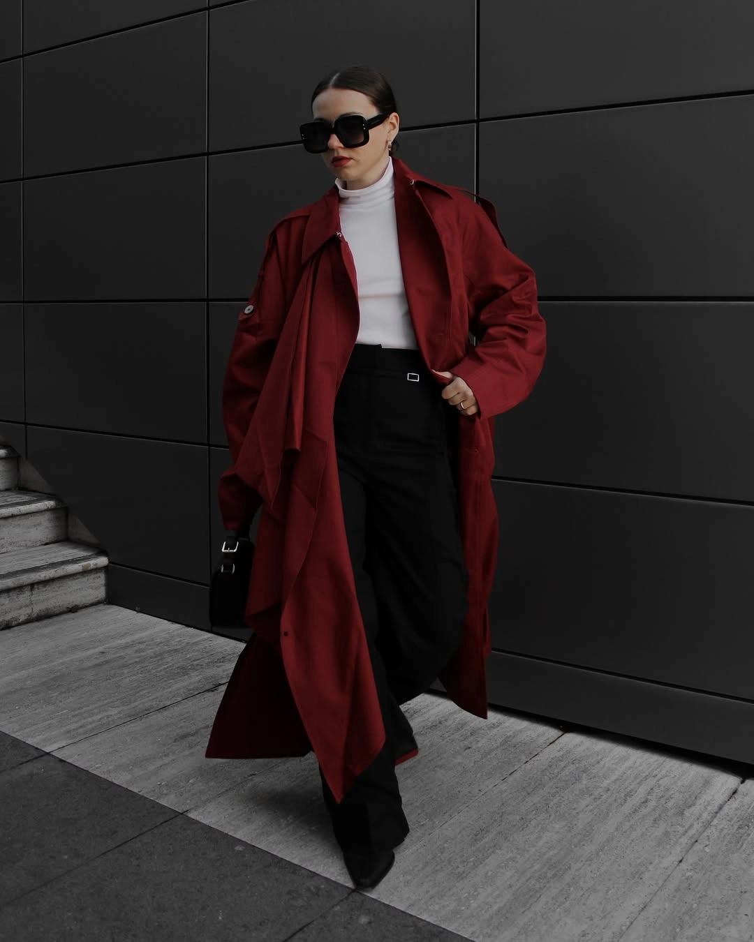 Woman in oversized burgundy coat, white turtleneck and black wide-leg trousers