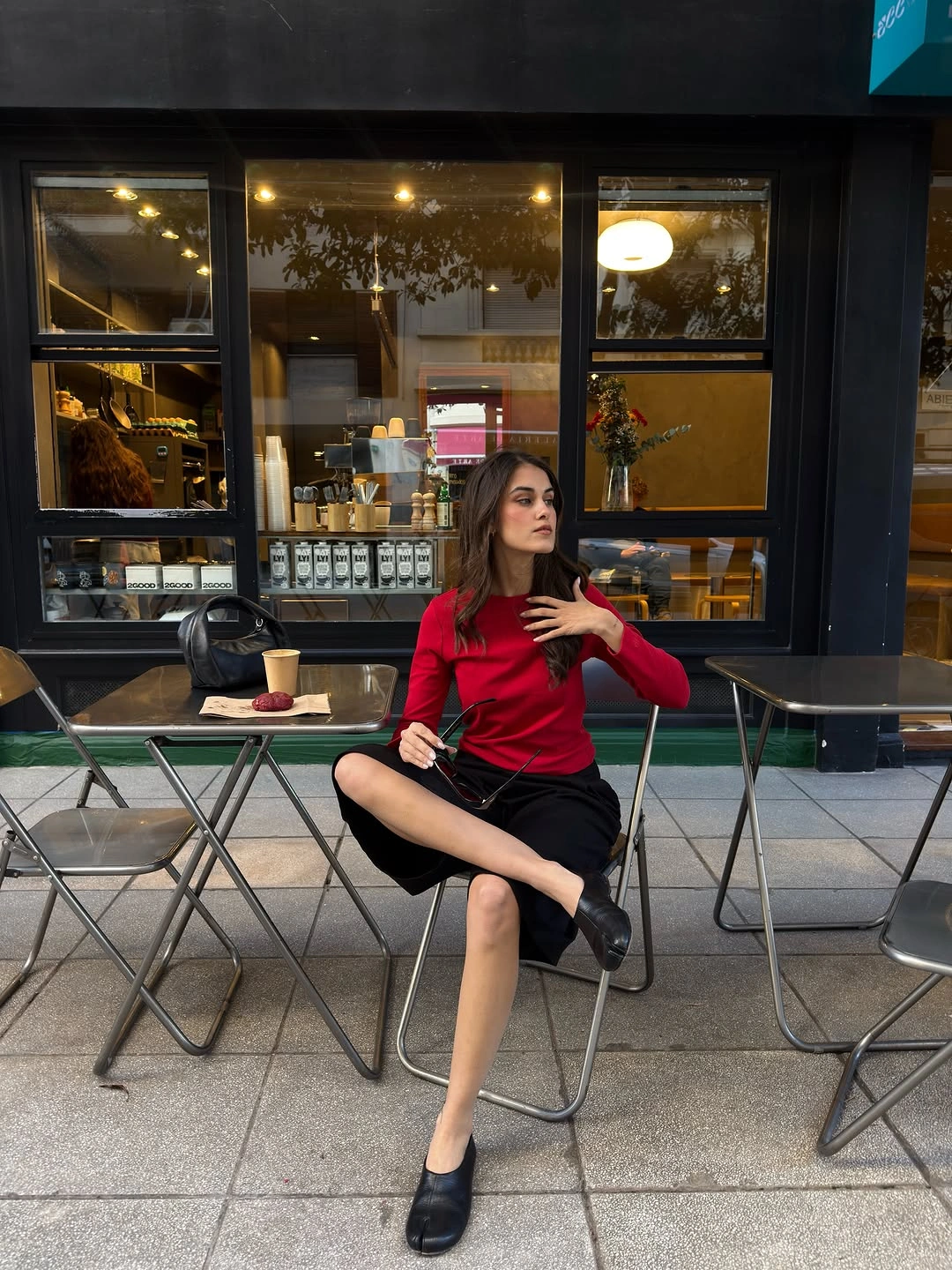 Woman in fitted red long-sleeved top, black skirt and black loafers