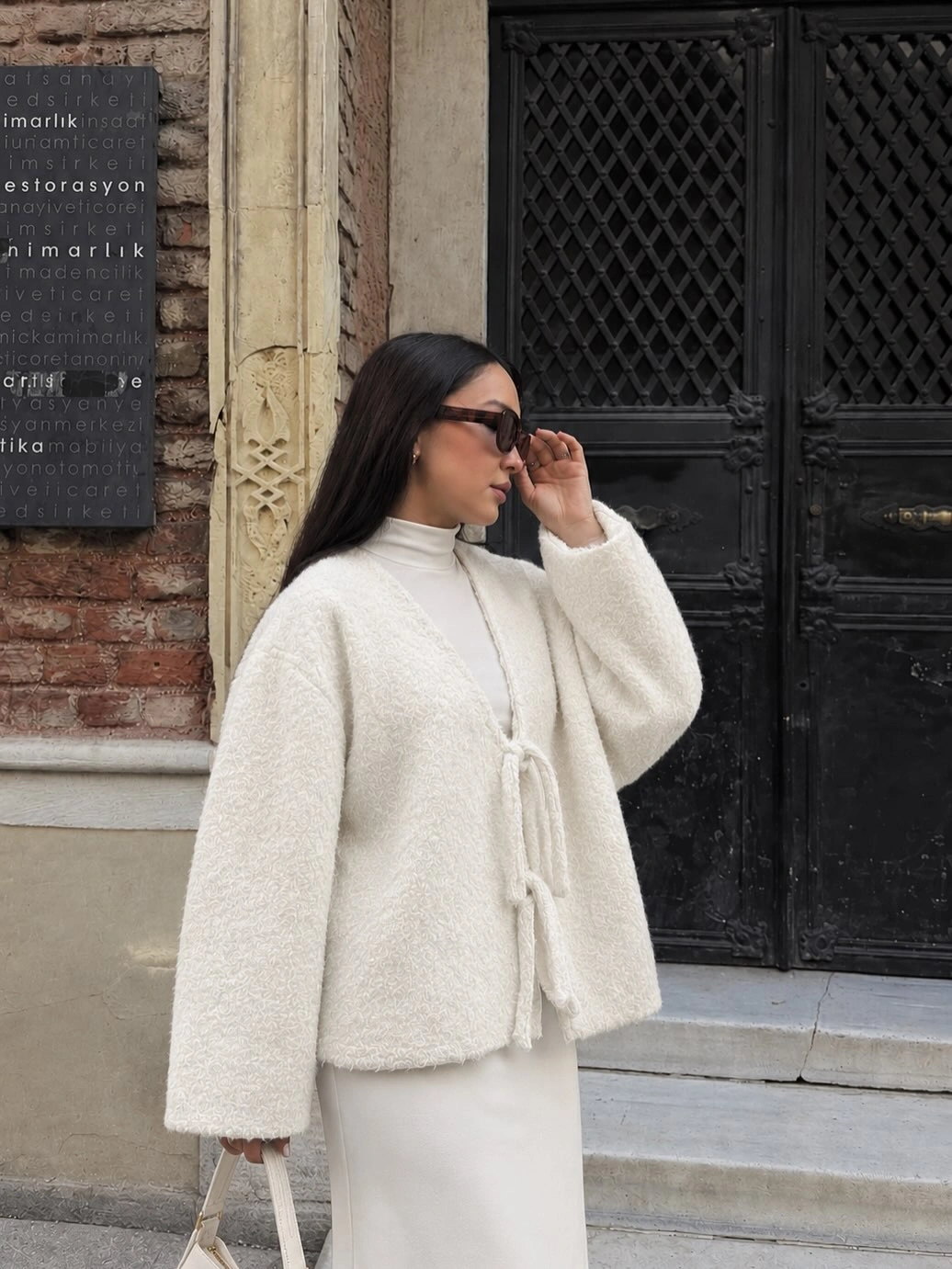 Woman in ivory textured tie-front jacket and long light skirt