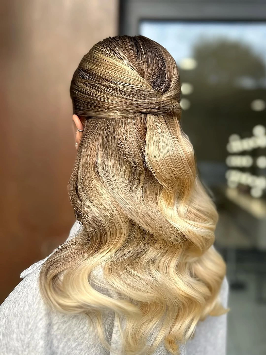 Blonde half-up hair with crossed sections and broad glossy waves