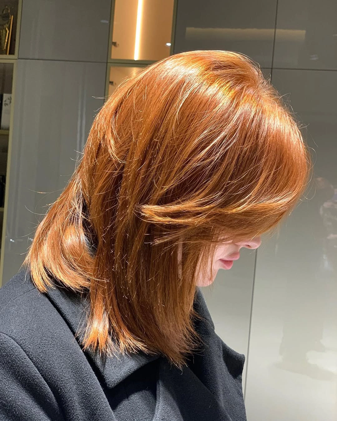 Copper-red layered hair with sweeping bangs and turned-out ends
