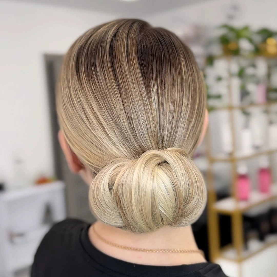 Sleek blonde hair in a rounded low nape bun