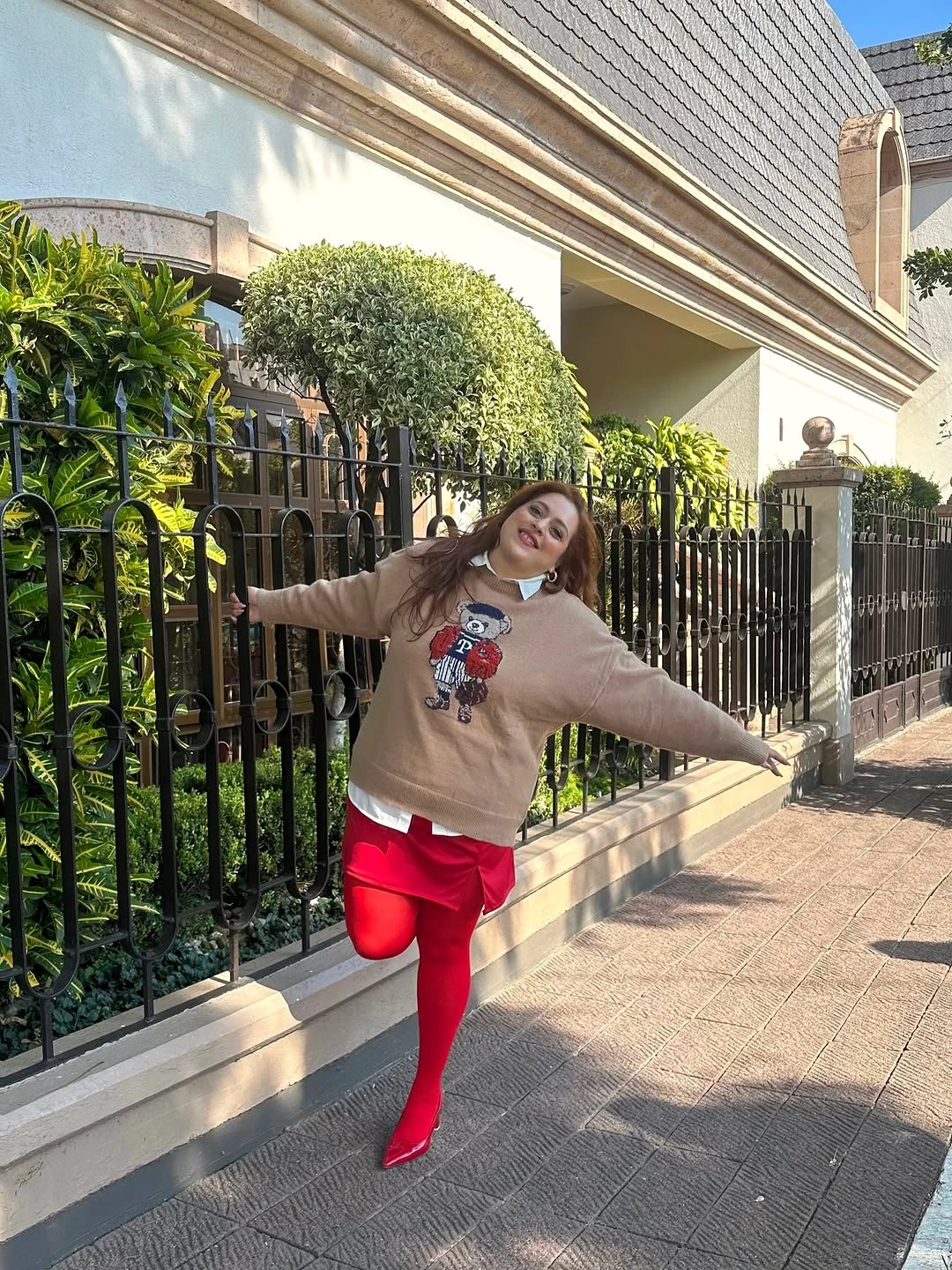 Oversized beige graphic sweatshirt with white collar red tights and pointed shoes