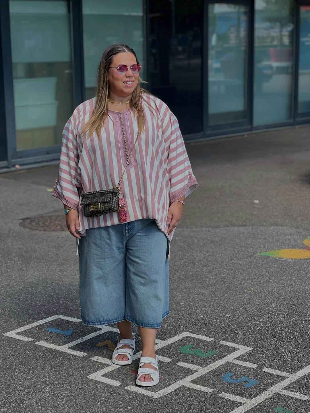 Loose pink striped blouse with long denim shorts and white sandals