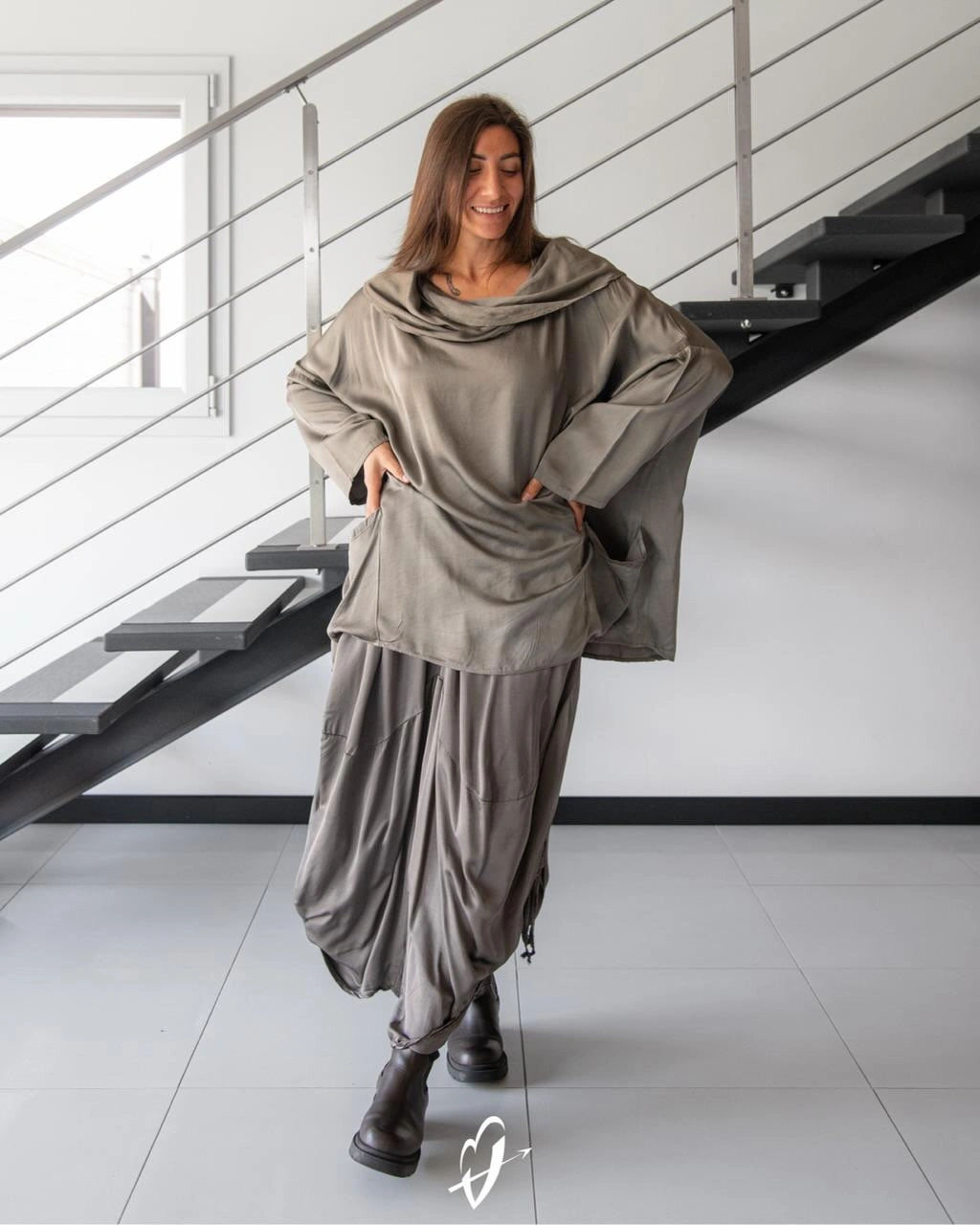 Loose gray draped top and gathered wide trousers with dark boots