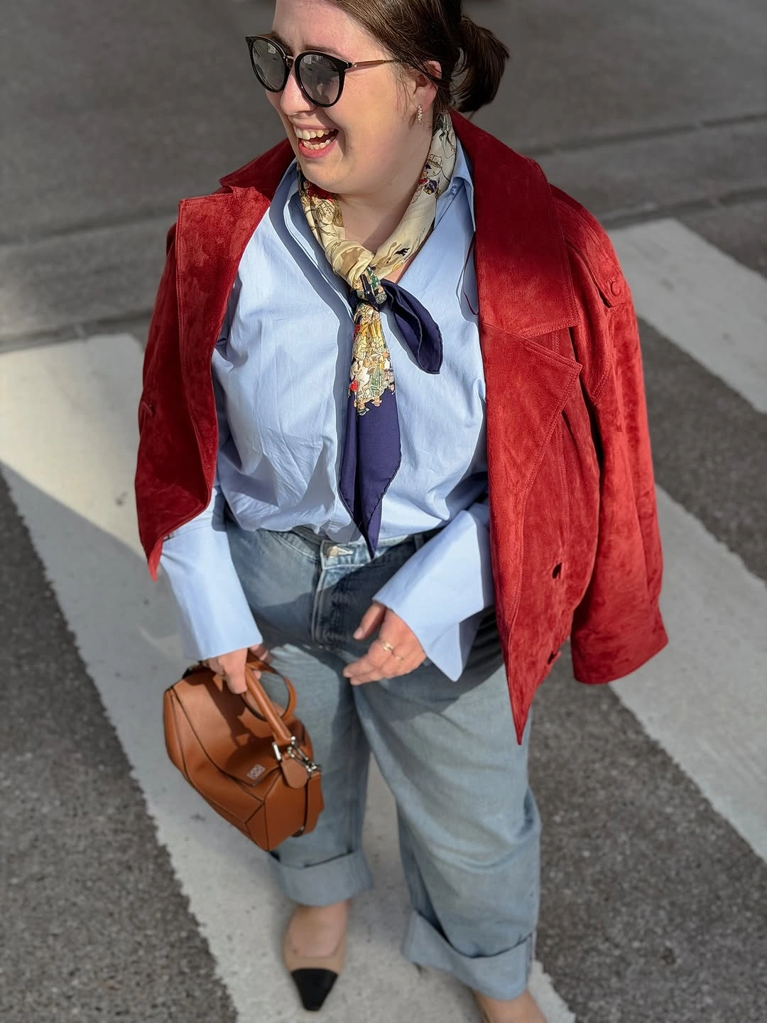 Red jacket over blue shirt with printed scarf cuffed jeans and handbag