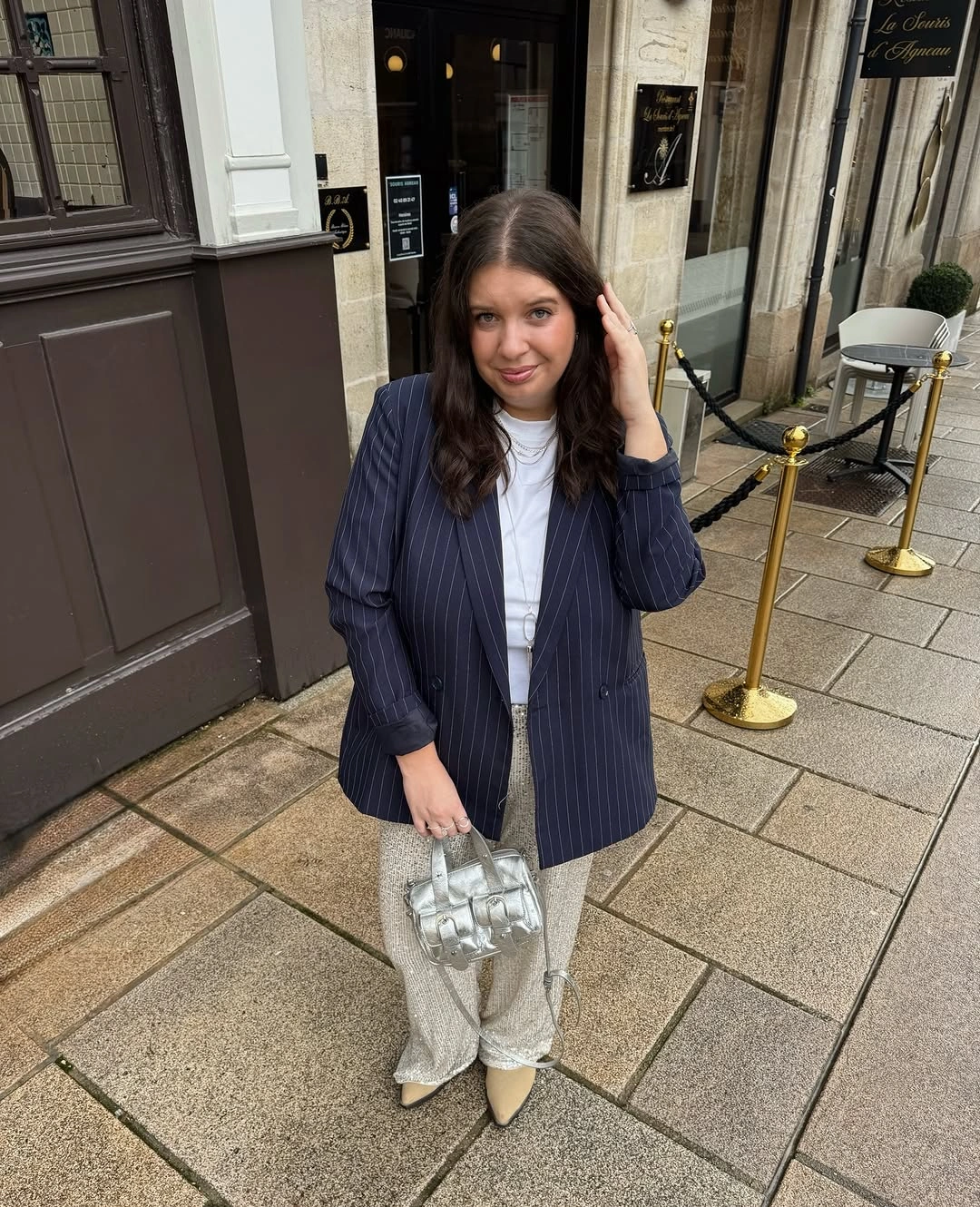 Navy pinstripe blazer over white top with pale trousers and silver bag