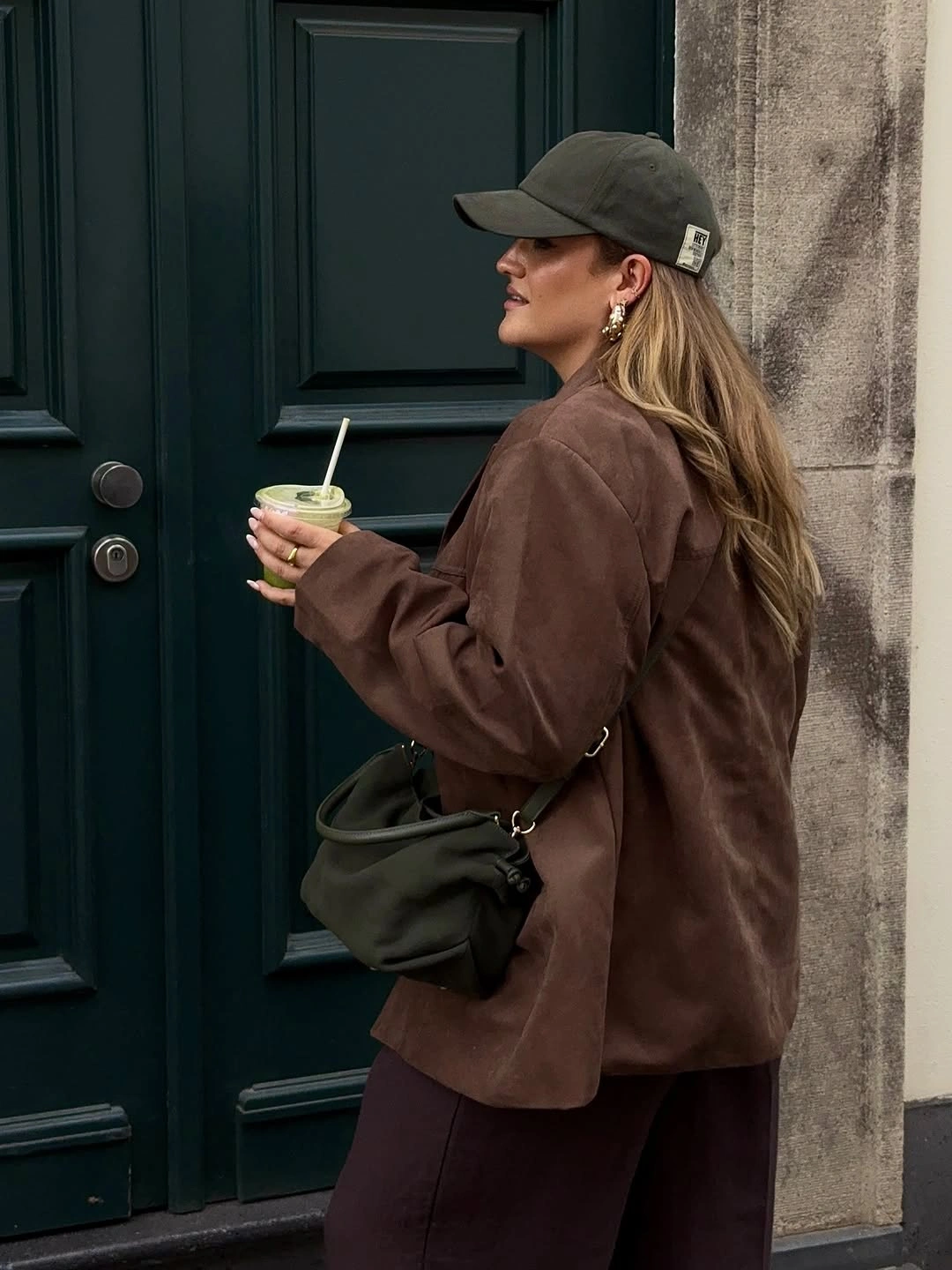 Oversized brown jacket with olive cap and crossbody bag