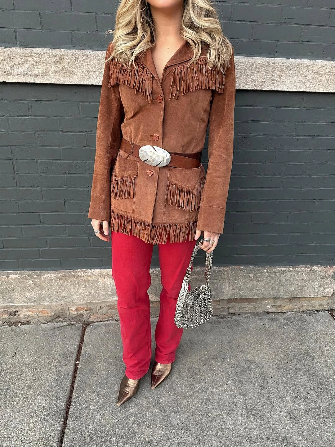 Brown fringed jacket red trousers and metallic accessories