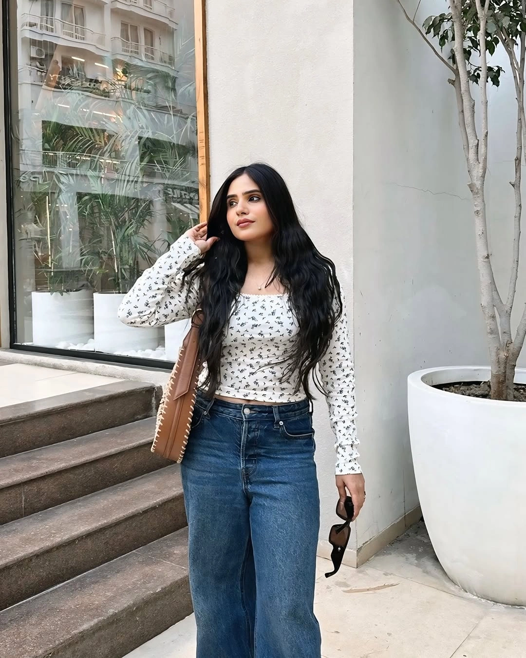 Woman in dark blue jeans and fitted white printed top