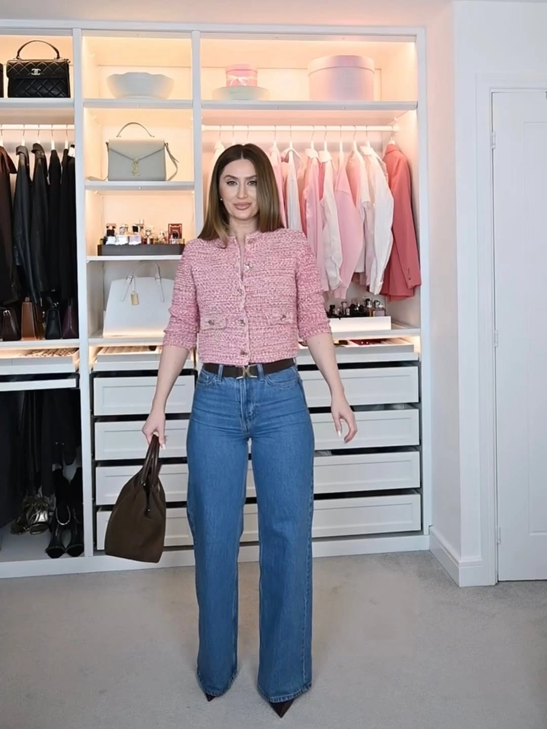 Woman in full-length blue jeans and cropped textured pink jacket