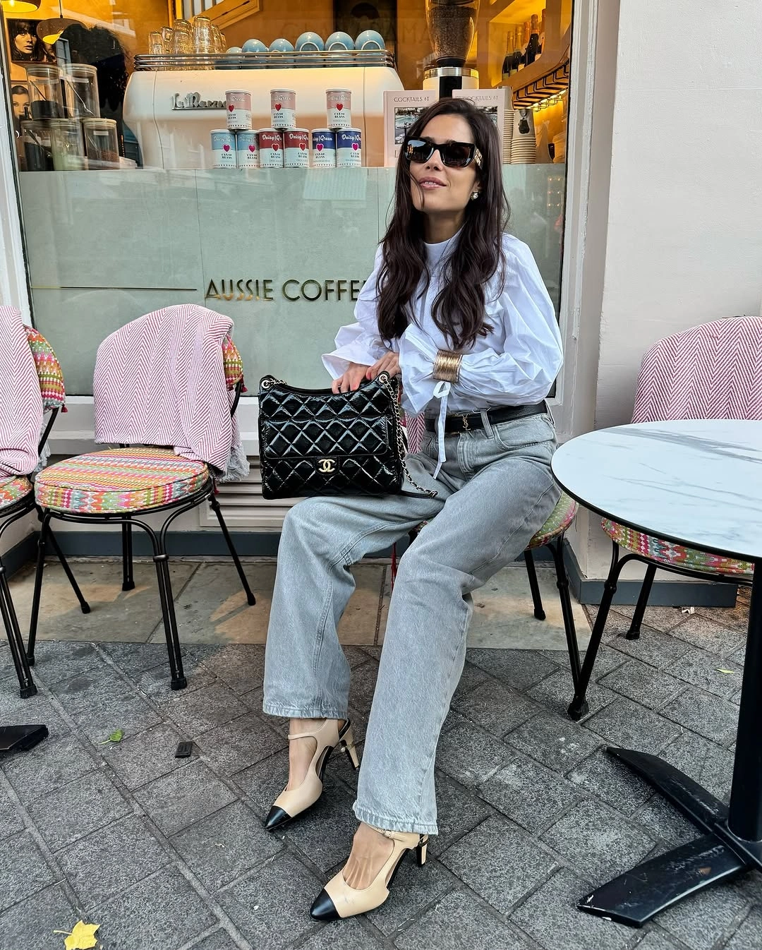 Woman in gray jeans, white blouse, and two-tone pointed heels