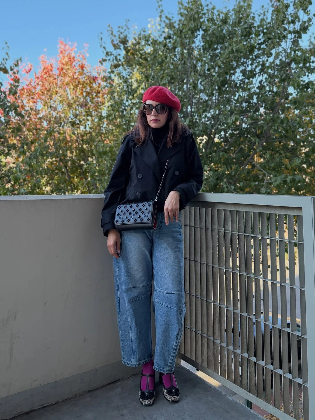 Woman in black coat, blue jeans, red beret, and pink socks