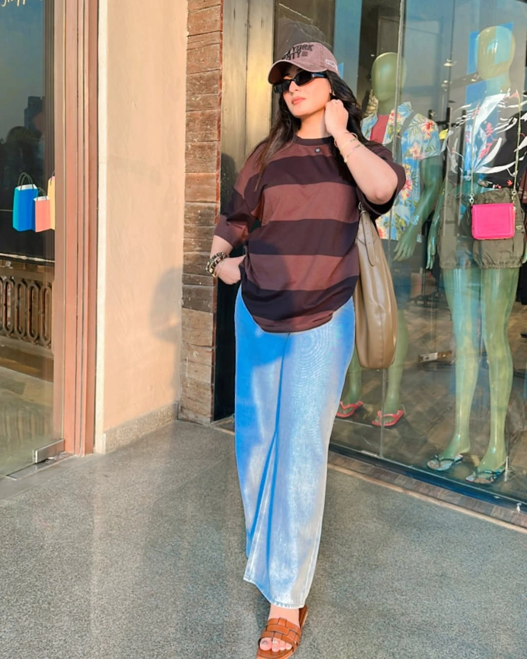 Woman in oversized striped tee, loose jeans, and orange sandals