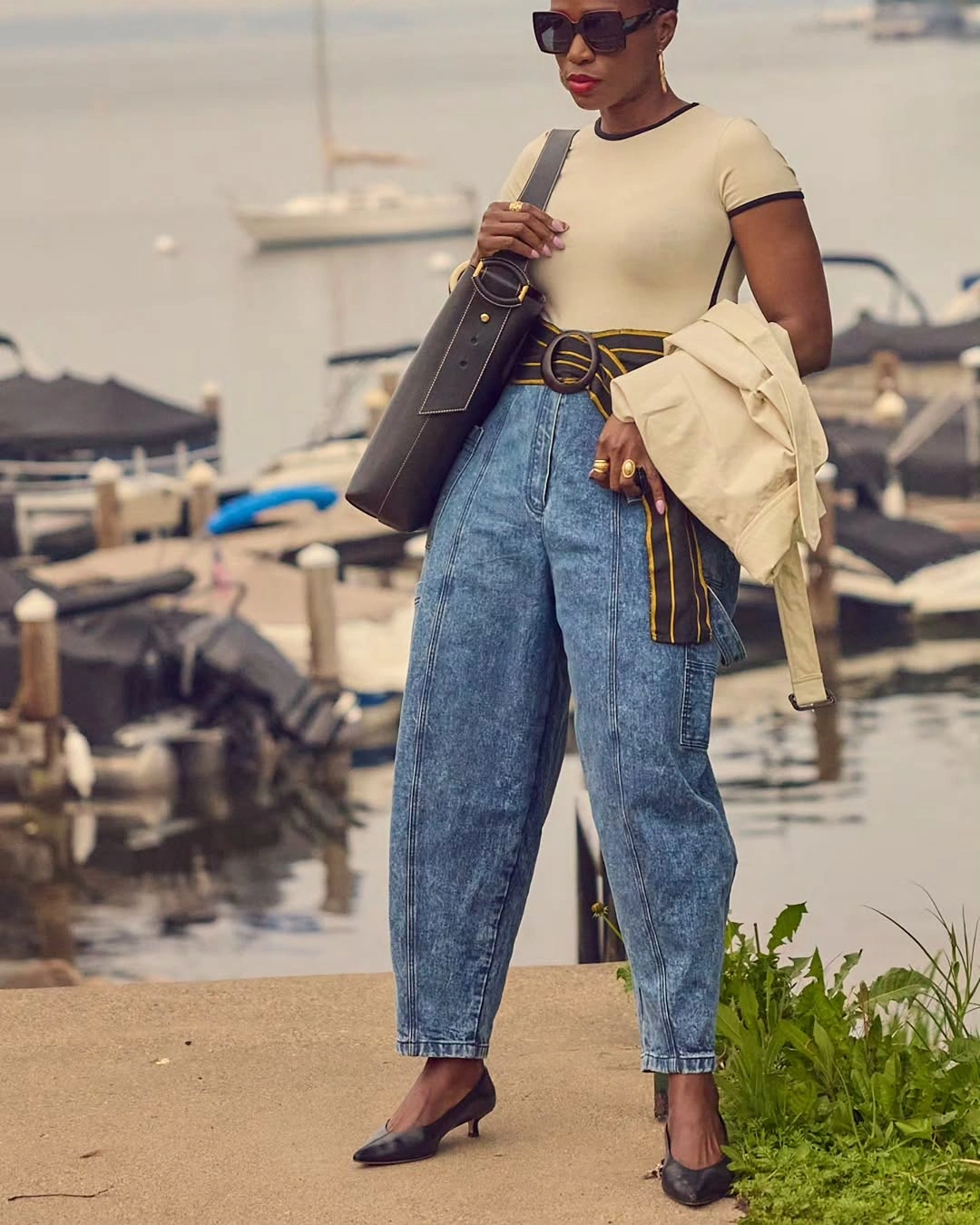 Woman in barrel jeans, fitted cream top, belt, and pointed heels