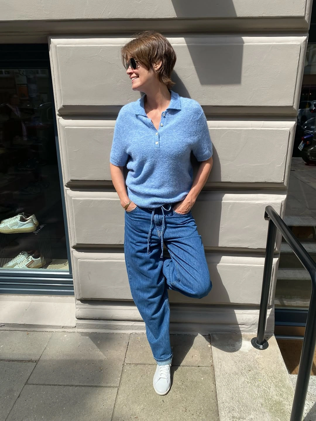 Woman in blue polo, relaxed jeans, and white sneakers