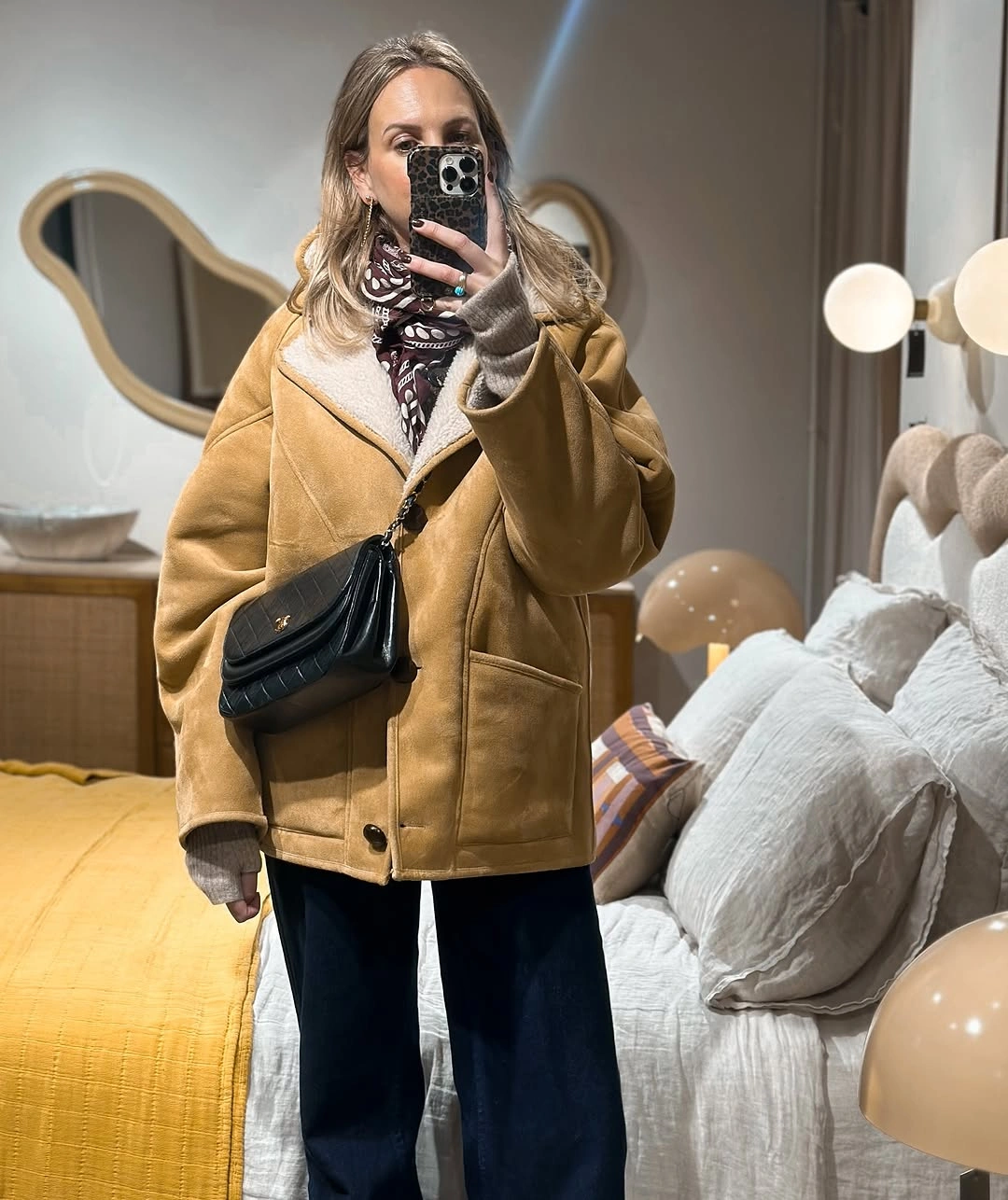 Tan boxy jacket with gray layers, patterned scarf, and dark trousers